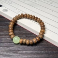 Braunes Holzperlenarmband mit grünem Jadestein auf Papier mit Kalligrafie-Dekor - Grünes Sandelholz Abakus Stil