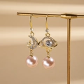 Detalle de pendientes asimétricos dorados con motivos de luna, estrella, planeta y perlas - Estilo de Gancho para la Oreja / Rosa