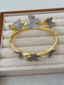 Dettaglio di due braccialetti a farfalla dorati con zirconi incastonati su velluto - 18K/Regolabile / Bangle