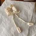 Close-up of cream fabric scrunchie with elegant tulip tassel streamers on paper background - Off White
