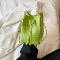Mini green woven drawstring bucket bag in premium leather finish shown held by hand - Fruit Green