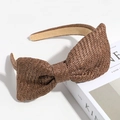 Detail of a brown woven straw headband with a large bow on a Kinfolk book - Dark Coffee