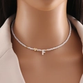 Close-up of beaded necklace featuring golden heart and white shell letter F pendant - Letter F