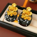 Detalle macro de pendientes vintage de flores doradas con base negra marbreada - Estilo Flor Oro Negro (Pin de Plata)