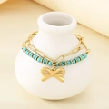 Detail of double-layer gold chain bracelet with turquoise beads and bow charm on a ceramic jar - Bowknot Turquoise Double Layer Style (KB203134-SXSJ)