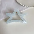 Detail view of the star-shaped light blue hair claw with durable gold metal spring - 11cm / Transparent Blue Star