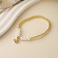 Elegant gold beaded bracelet with white pearls and red cherry charm on beige background - E000421YS-Red Enamel Cherry