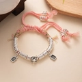 Detail of pink hand-woven bracelet with silver lion charm and traditional metal charms - L393-3 Yellow Wealth God (Pink Rope)
