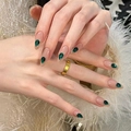 Handmade almond press-on nails in nude with emerald green teardrop gemstones on plush background - By2000 Radiant Colors / Phototherapy Glue Style