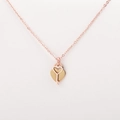 Macro detail of rose gold heart and key pendants on a premium white leather surface - Rose Gold