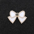 Macro detail of white enamel bow charm with pearl border and center rhinestone - Gold Base White Bow