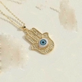 Makroaufnahme der goldenen Hamsa-Hand mit blauem bösem Blick und Ornamenten - Gravierte Hamsa Hand