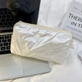 Detailed view of white quilted butterfly pattern makeup bag next to a laptop on white fabric - Small Bow Beige