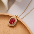 Gold plated necklace featuring an oval pendant with a red gemstone and crystal halo - Red