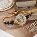 Detailed view of heart-shaped gold quartz watch with rhinestones and black heart bracelet - Black