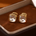 Macro shot of gold-plated square blue crystal stud earrings in a luxury jewelry box - Clear