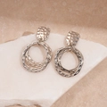 Close-up of silver geometric hammer-textured earrings on a natural white stone - Silver