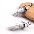 White turquoise hexagonal column pendants with silver metal mount on wood and white surface - Howlite