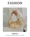Detail of champagne gold ruched cloud bag showing smooth faux leather texture and handle - Gold