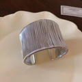 Macro detail of wide silver wire-wrapped cuff bracelet on a white ceramic plate - Silver Wrapped Wide Cuff Style