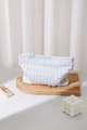Detalle del neceser de tela a rayas con nudo decorativo sobre soporte de madera - Trébol de Cuatro Hojas Azul