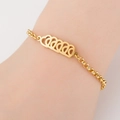 Detail of a gold titanium steel bracelet featuring hollow heart charms on a female wrist - 5 Hearts / Gold