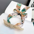 Detail des floralen Haarreifs mit beige Schleife und Vintage-Blumenmuster auf Buch - Orange + Grüne Blumen