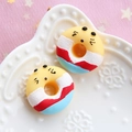 Macro shot of 3D resin donut charms with cute faces on a white embossed ceramic plate - Yellow Base - White Red Blue