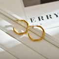 Minimalistische vergoldete unregelmäßige Wellenohrringe auf weißem Lederständer - Kreis / Gold Kreise