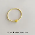 Macro detail of high-elasticity yellow hair tie with a matching matte heart charm - Yellow
