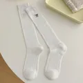 White knee-high slouch socks with black bow embroidery and ribbed knit texture - One Size / White