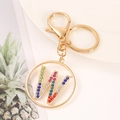 Detail of golden metal keychain featuring colorful rhinestone letter W on white plate - Letter W