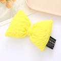 Close-up of a yellow quilted leather bow accessory with creative fabric label detail - Yellow