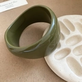 Detailed close-up of wide olive green acrylic resin faceted bangle on a ceramic plate - Thickened Glossy Style / Olive Green
