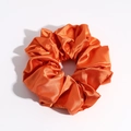 Detail view of glossy orange satin scrunchie showing smooth fabric texture and elastic design - Orange Small