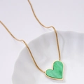 Golden snake chain necklace with green malachite heart pendant on a white tray - Green