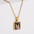 Dettaglio di un ciondolo rettangolare in oro 18k con lettera M su intarsio di conchiglia - Taglia M