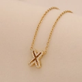 Detail of gold cross pendant necklace with sparkling inlaid stones on O-chain - Letter X