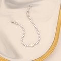 Macro view of silver tone sparkling tennis bracelet with hollow clover charm on gold-rimmed tray - Silver Clover Motif Style (13#)