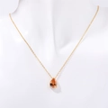 Golden necklace with pear-cut orange zircon pendant shown on a white mannequin bust - November Citrine