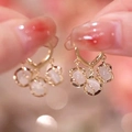 Close-up of golden heart earrings featuring three dangling milky cat-eye stone pendants - Gold Heart Cat's Eye Drop
