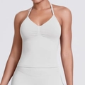 Detail view of seamless white halter yoga top showing ribbed hem and deep V-neck texture - Feather Beige