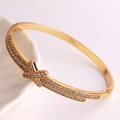 Dettaglio ravvicinato del bracciale dorato a forma di X con micro zirconi incastonati - Design a Croce X Micro Pavé (Stile 7)