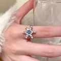 Elegant snowflake-shaped silver alloy ring featuring a central blue gemstone on a finger - Snowflake Zirconia Ring