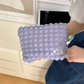 Nahaufnahme der fliederfarbenen Make-up-Tasche mit Bubble-Struktur und Markenetikett - Blasen-Dunkelviolett