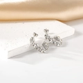 Elegantes pendientes en forma de C plateados con circonitas sobre un pedestal de piedra blanca - Color Acero