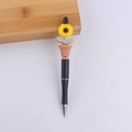 Close-up of a creative black plastic pen featuring a yellow sunflower silicone top - Yellow