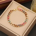 Close-up of gold stainless steel necklace with pink and blue enamel charms on display - Bracelet