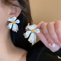 Squisiti orecchini a fiore 3D bianchi con centro dorato indossati da una modella in primo piano - Petalo Bianco Stame Oro