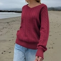 Women's V-neck red cable knit sweater with ribbed cuffs shown in a natural beach setting - S / Burgundy